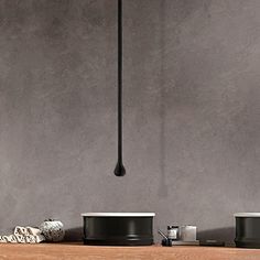 three black pots are sitting on a wooden shelf next to a light fixture that is hanging from the ceiling