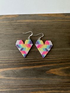 a pair of heart shaped earrings sitting on top of a wooden table