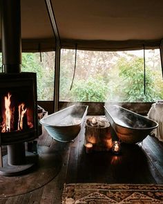 two bath tubs sitting on top of a wooden floor next to a fire place