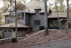 a large house in the woods surrounded by trees and leaves, with stairs leading up to it's front door