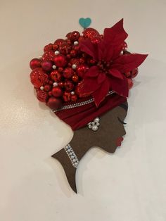 a woman's head is adorned with red ornaments and poinsettia leaves