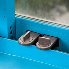 two gray door handles on a blue window sill