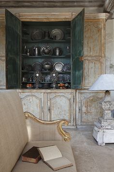 a couch sitting in front of a cabinet filled with dishes