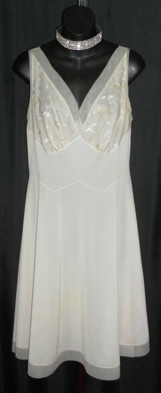 "Made by Vanity Fair, color is an off white, antique white, light beige, whichever you would like to call it, so pretty. This halter style gown is ultra flattering with satin stitched embroidery on the bust and chiffon trim on the bodice and hemline. I do see some light colored stains on the lower half of the gown, you may be able to see them in the photo of the hemline. I did launder but they didn't seem to come out. Relatively light so they aren't as obvious. Bust 38\" Waist 32\" Hips up to 46 Fitted Cream Nightgown For Wedding, Elegant Sleeveless Cream Nightgown, Elegant Cream Sleeveless Nightgown, Elegant Cream Wedding Nightgown, Feminine White Nightgown For Evening, Elegant Cream Sheer Nightgown, Feminine White Evening Nightgown, Fitted Sheer Cream Nightgown, Sleeveless Cream Nightgown For Wedding