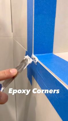 a person holding a pair of scissors in front of a blue and white wall with the words epoxy corners on it