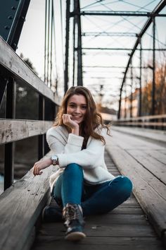 a woman sitting on the ground next to a bridge