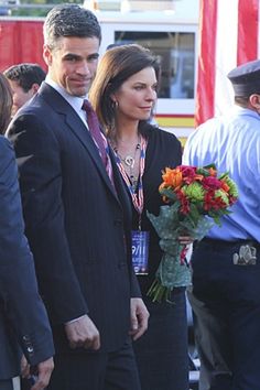 two people standing next to each other in front of a firetruck with flowers