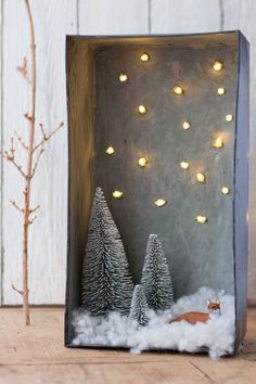 a small box with some lights on it and trees in the snow next to it