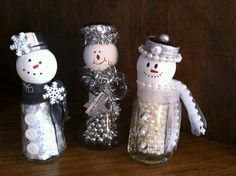 three snowmen made out of glass bottles sitting on a wooden table next to each other