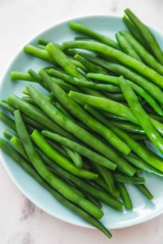 green beans on a white plate sitting on a marble counter