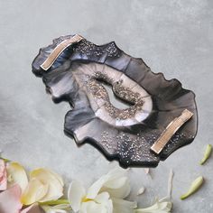 a black and white plate with some flowers on the table next to it, which is shaped like an ovoid