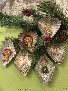 christmas ornaments are arranged on a table with pine cones and holly branches in the center