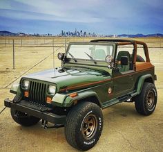 a green jeep parked on top of a dirt field