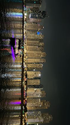 the city skyline is lit up at night with bright lights on it's skyscrapers