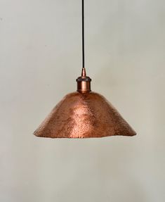 a copper colored pendant light hanging from a ceiling