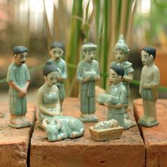 a group of figurines sitting on top of a brick wall next to plants