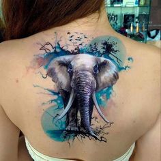 an elephant tattoo on the back of a woman's shoulder