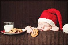 a baby wearing a santa hat and eating cookies