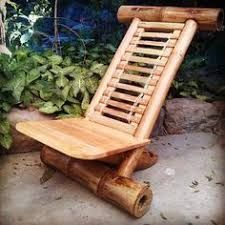 a wooden chair sitting on top of a cement floor next to plants and rocks in a garden