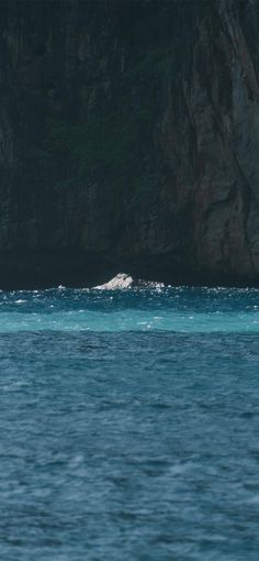 a large body of water next to a rocky mountain side with a white object in the middle