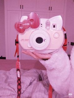 a person holding up a camera in front of their face with hearts attached to it