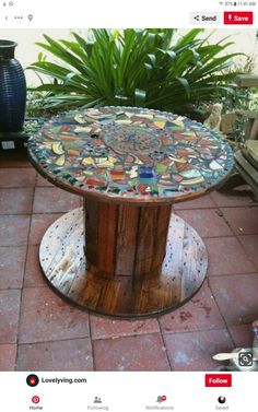 a table made out of glass and wood on top of a brick floor next to a potted plant