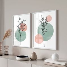 two framed art prints on a wall above a dresser with vases and other items