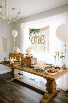 a wooden table topped with lots of plates and food next to a white balloon hanging from the ceiling