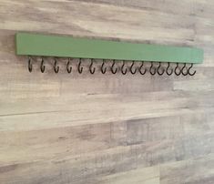 there is a green rack on the wall with several hooks hanging from it's sides