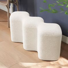 three white stools sitting on top of a hard wood floor next to a plant