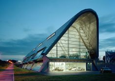 a large triangular shaped building with cars parked in it's parking lot at night