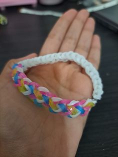 a hand holding a colorful bracelet on top of a table