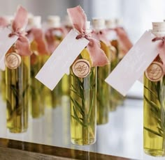 several small bottles filled with green liquid and tied with pink ribbon, each containing an individual's initials