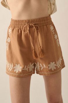 Linen-blend shorts. Floral embroidery. Elastic waist with tassel drawstring. Side pockets. Wide leg. Thigh length. Relaxed fit. 70% Rayon, 30% Linen. Imported. Designed in LA. Model wears size S. Bohemian Embroidered Beige Bottoms, Beige Bohemian Embroidered Bottoms, Casual Embroidered Beige Bottoms, Bohemian Short Length Bottoms With Drawstring, Embroidered Cotton Shorts For Vacation, Bohemian Embroidered Cotton Shorts, Casual Floral Embroidered Bottoms For Beach, Casual Floral Embroidery Bottoms For Beach, Casual Tasseled Bottoms For Vacation