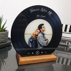 a personalized photo frame with a wooden base on a table next to a potted plant