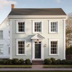 a white two story house with black door and windows