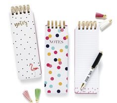 three notepads with different designs on them and one has a pen in it