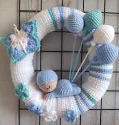 a crocheted wreath is hanging on the wall with two small knitted items