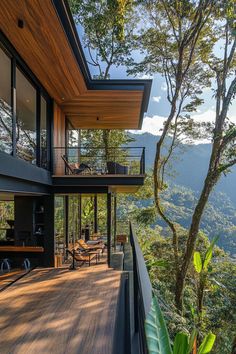 a house that is on the side of a hill with lots of trees and mountains in the background