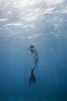 a person swimming in the water with a fish on it's back and long tail