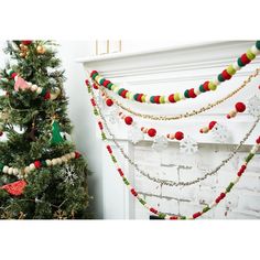 a decorated christmas tree in front of a fireplace with garland on it's mantle