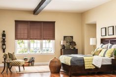 a bed room with a neatly made bed next to a window and a wooden floor