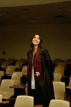 a woman standing in front of rows of chairs with her graduation gown draped over her shoulders