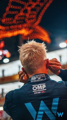 a man with blond hair is wearing a blue shirt and has his back turned to the camera