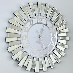 a clock that is on the wall and has mirrors around it's edges in different sizes