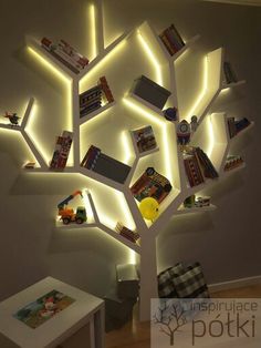 a tree made out of books is lit up with white lights and some pictures on it