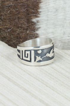 This sterling silver ring was made by Hopi silversmith Timothy Mowa. The inside is stamped sterling.Size: 12Length: 1"Free shipping on all orders! We ship with USPS and always include tracking. All orders ship within a day of payment.Returns are accepted up to 30 days after you receive your order. Just send us a message. Our shop offers cash back or store credit. The item must be returned in new condition. Artisan Engraved Sterling Silver Ring 925, Sterling Silver Engraved Wide Band Ring, Artisan Sterling Silver Engraved Hallmarked Ring, Stamped Sterling Silver Wide Band Jewelry, Artisan Sterling Silver Ring With Etched Details, Artisan Sterling Silver Etched Rings, Artisan Sterling Silver Wide Band Ring, Symbolic Sterling Silver Stamped Rings, Symbolic Stamped Sterling Silver Rings