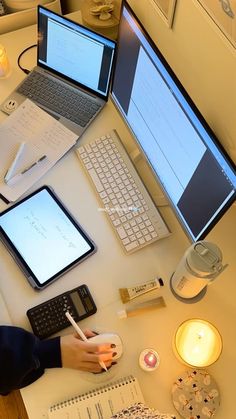 a person sitting at a desk with two laptops and three computers on it,