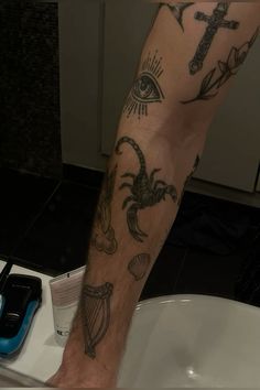 a man's leg with tattoos on it sitting in a sink next to a blue toothbrush