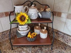 three tiered trays with sunflower and mugs on them in a kitchen